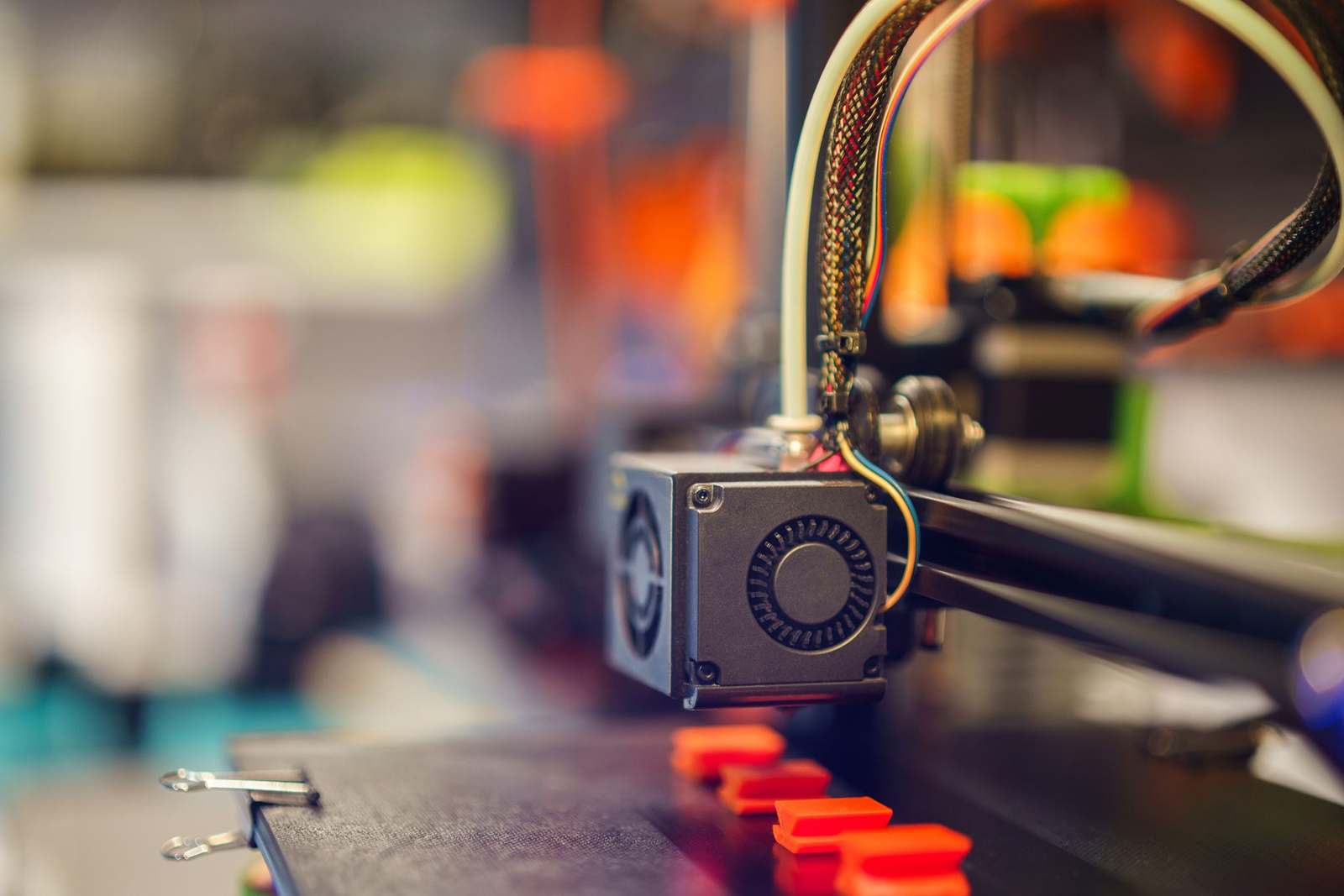 A 3D printer extruding red filament during a build