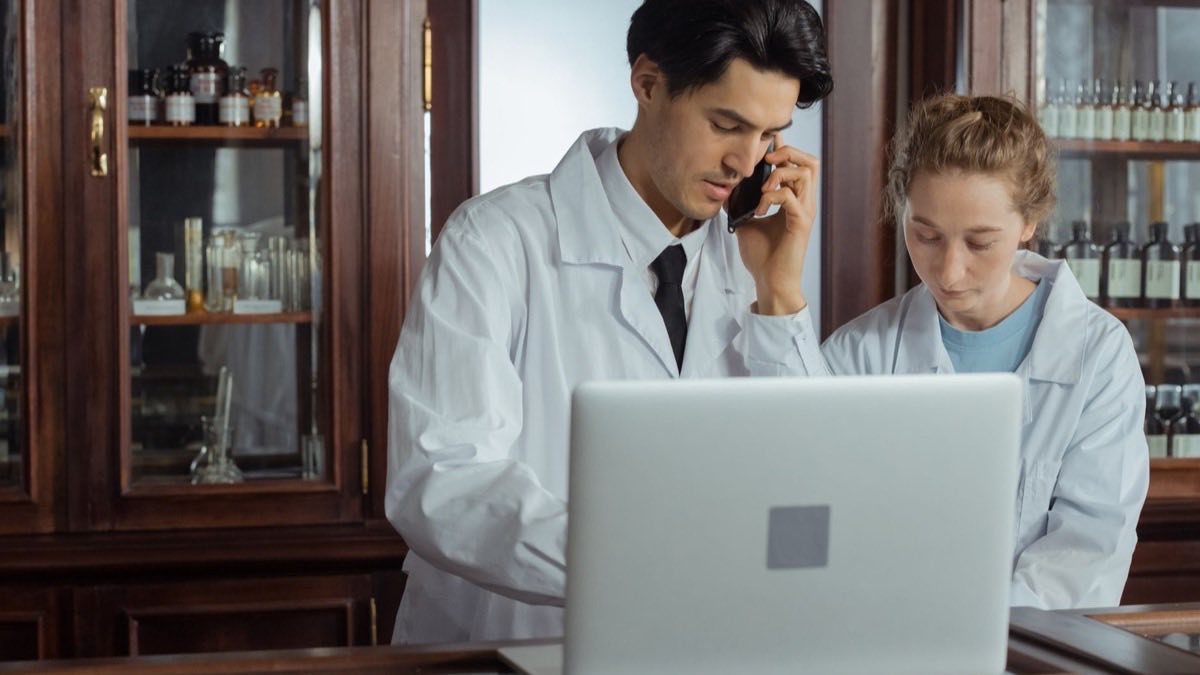 Two pharmacists reviewing medication records together on a laptop