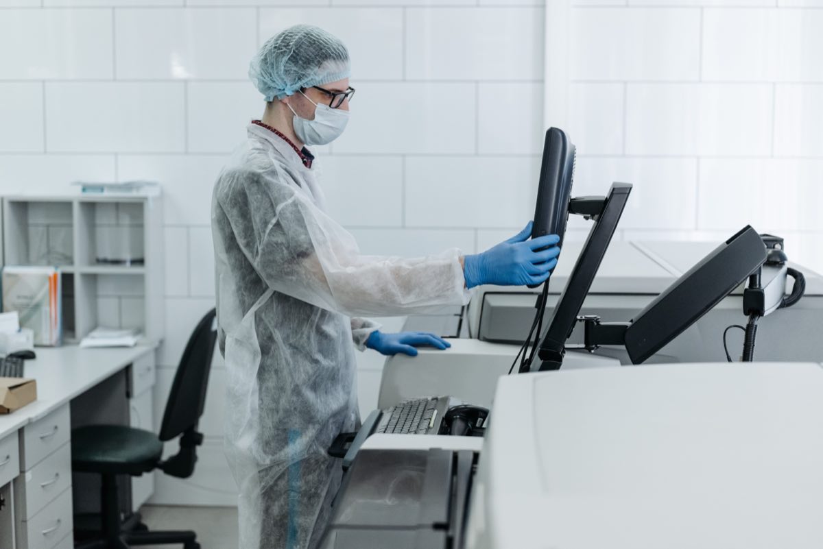 A gowned scientist operating laboratory test equipment