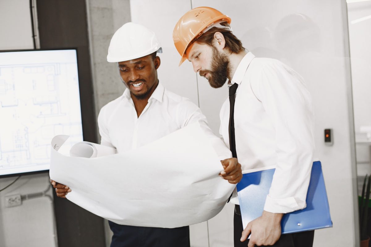 Two engineers comparing technical drawings at a worksite table