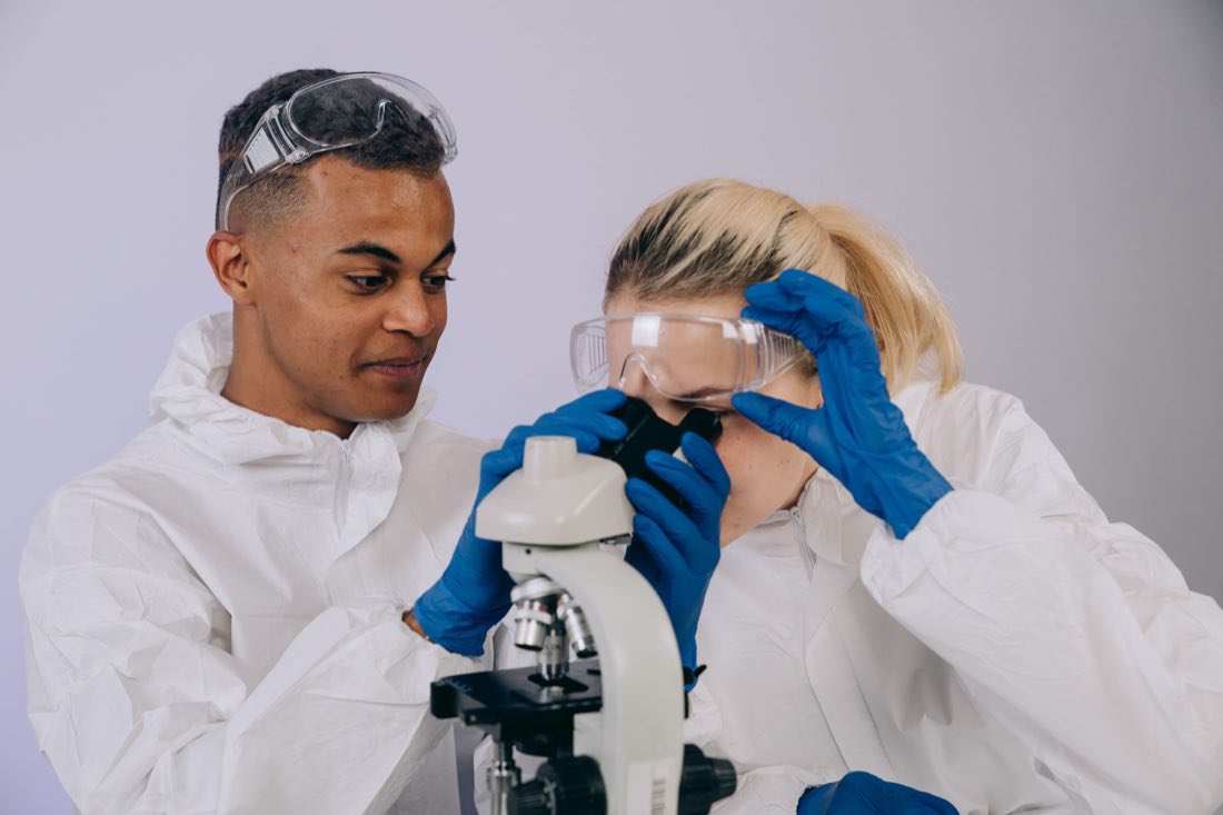 Two scientists reviewing a sample under a microscope