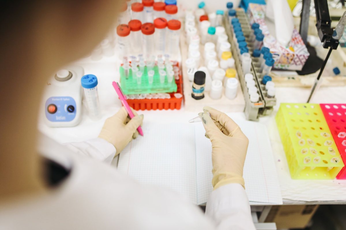 Researcher recording results at a laboratory bench of reagents and assay plates