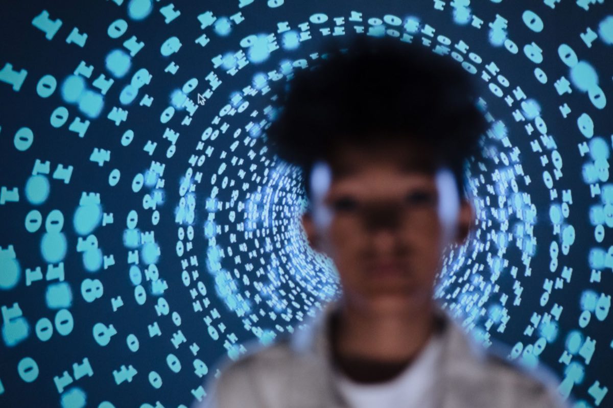 A person silhouetted against a swirling projection of digital code