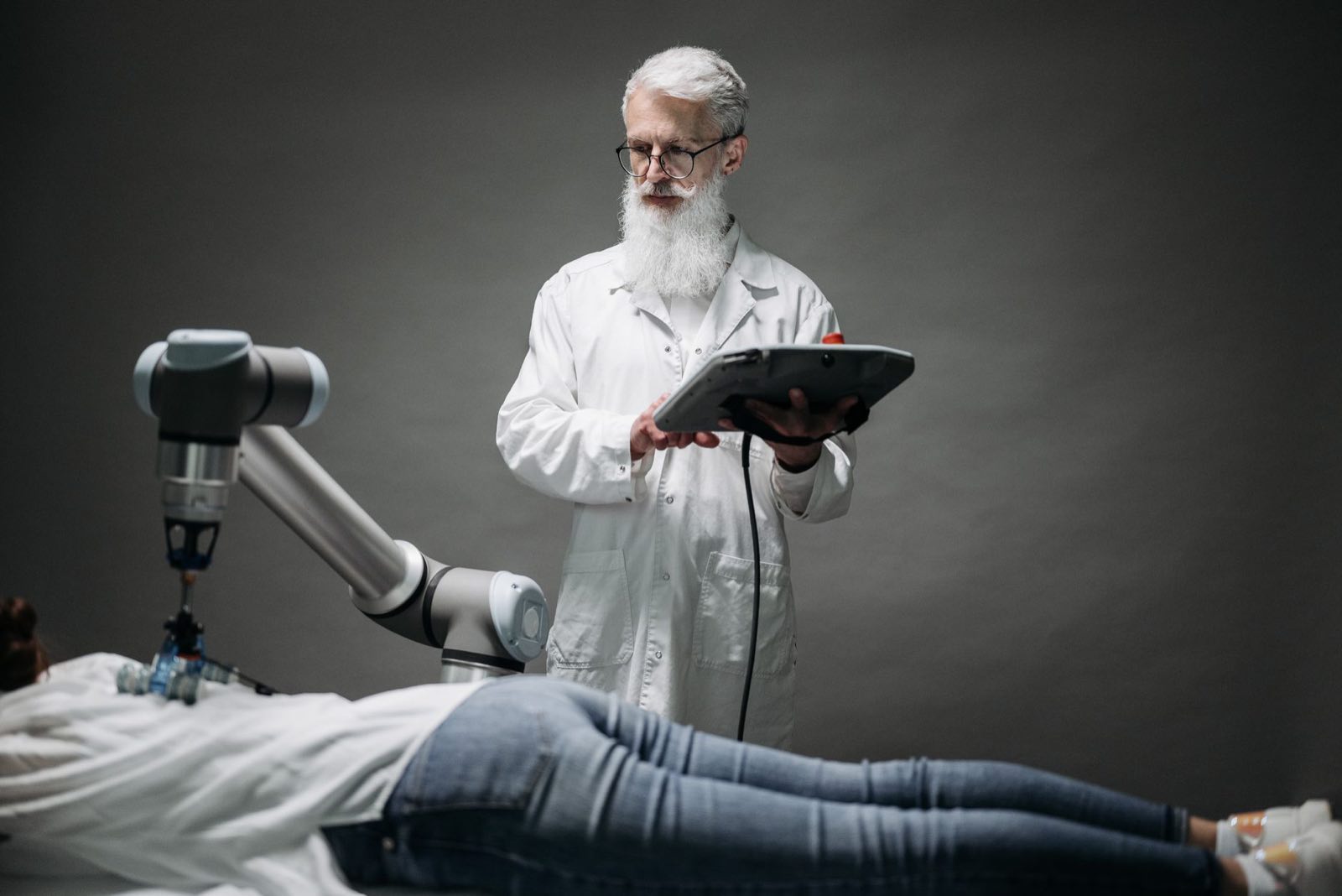 A scientist directs a robotic arm over a patient using a tablet