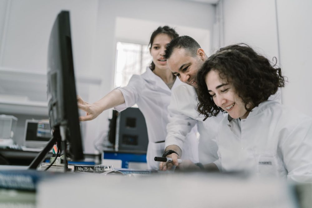 A group of scientists working together at a computer in a bright lab