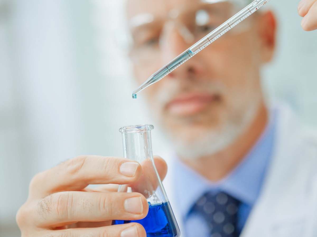 A scientist pipetting into a flask in a sterile laboratory environment