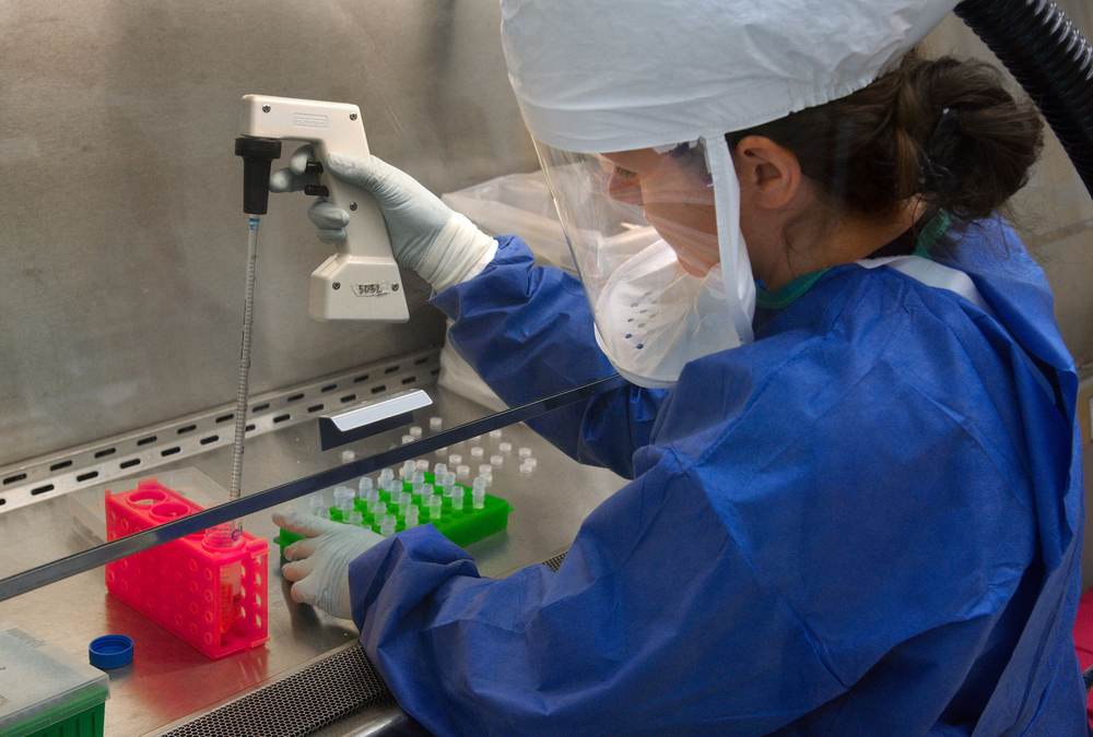 A scientist in protective gear handling laboratory equipment