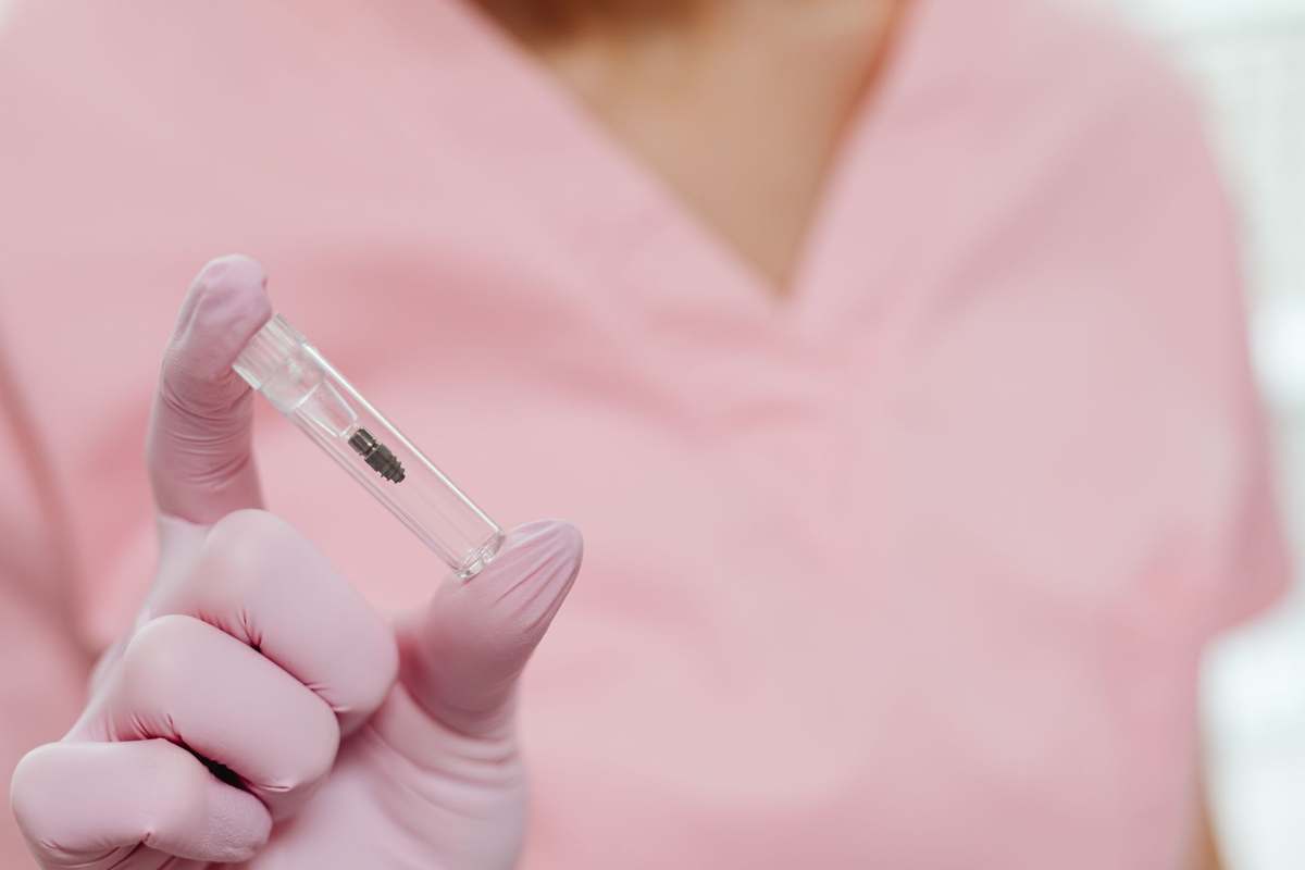 A clinician holding a packaged dental implant
