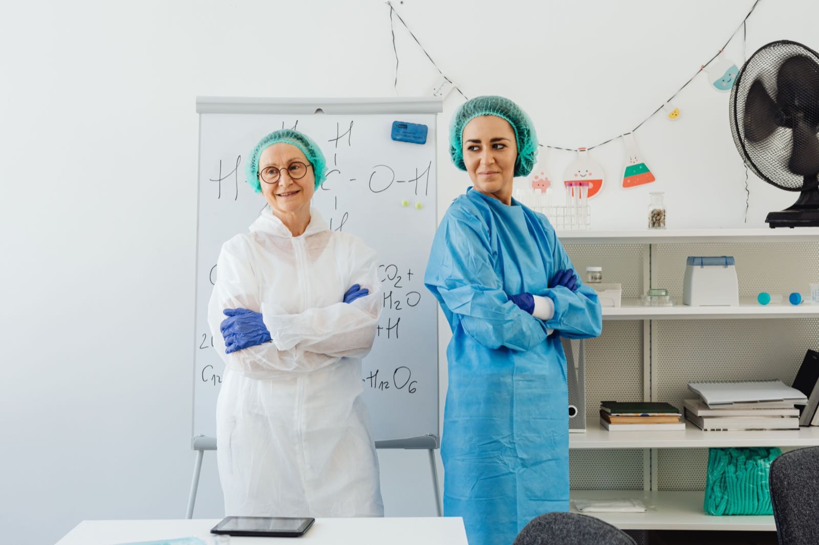 Two scientists in laboratory protective gear standing together in a bright lab