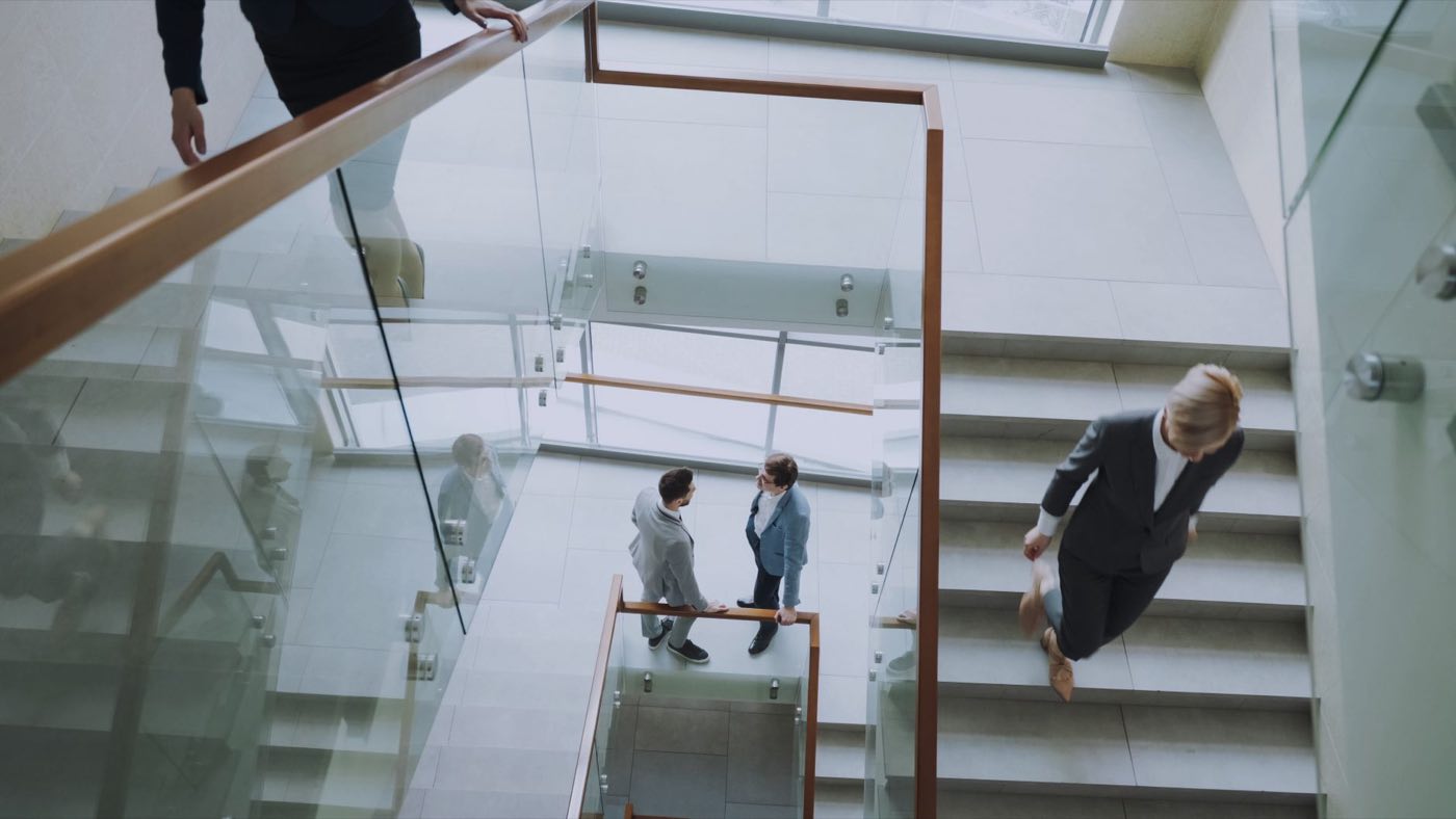 Consultants in conversation on the glass staircase of a bright modern office