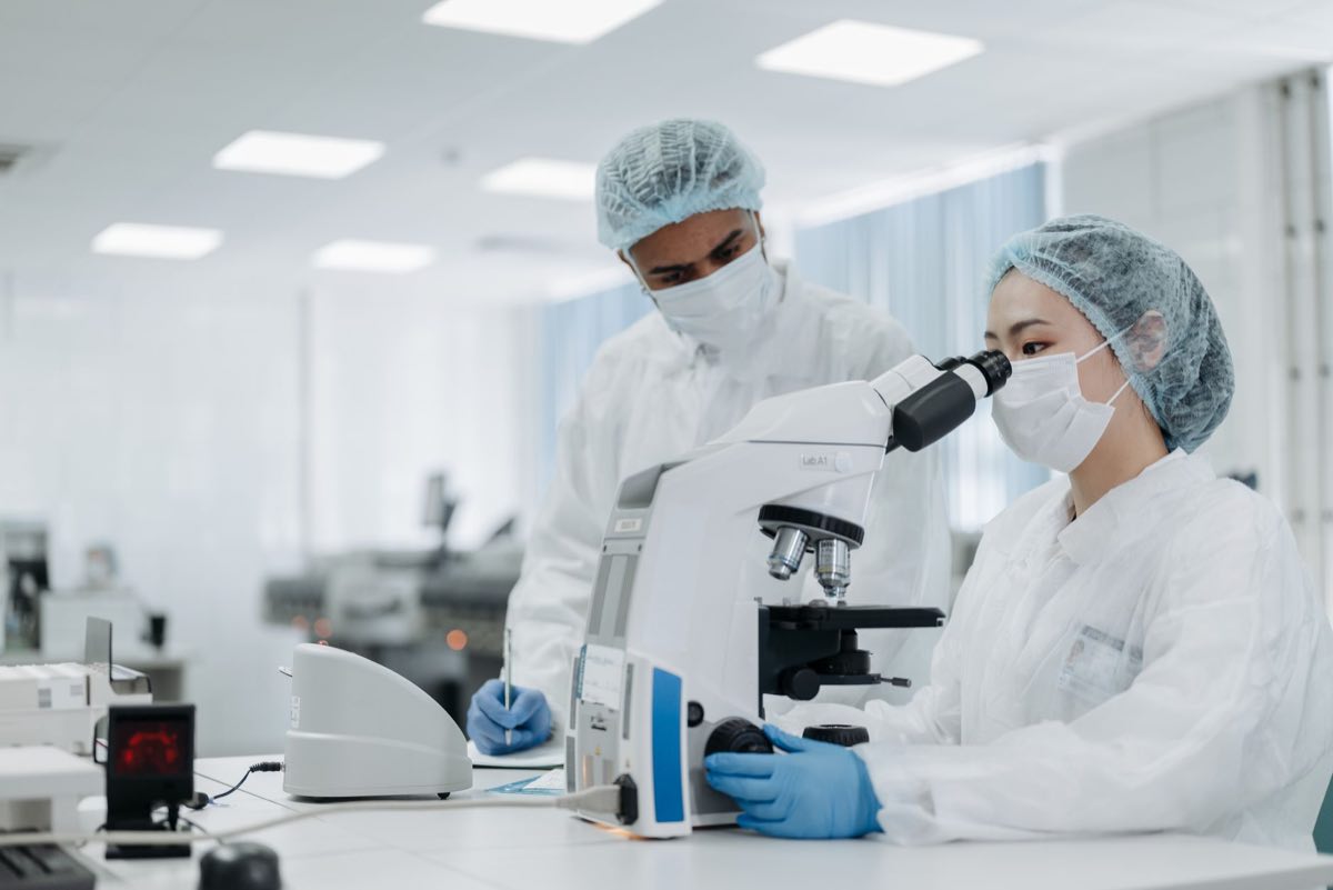 Scientists in protective suits examining samples in a cleanroom setting