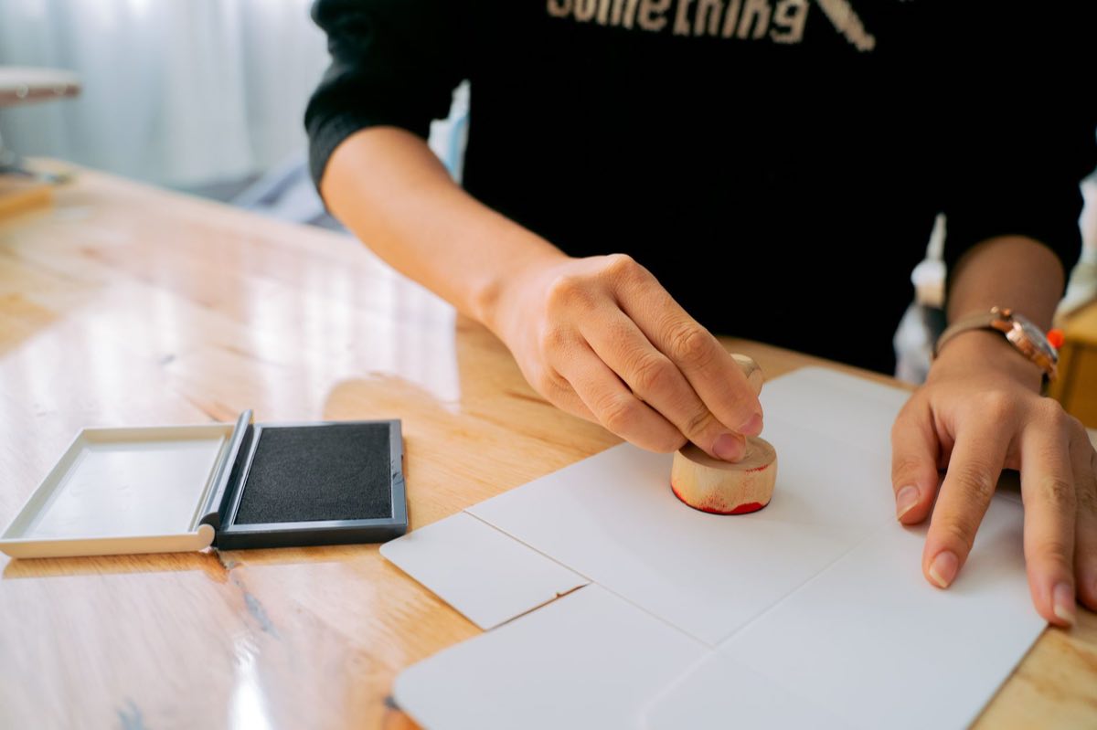 A hand stamping an approval on a document