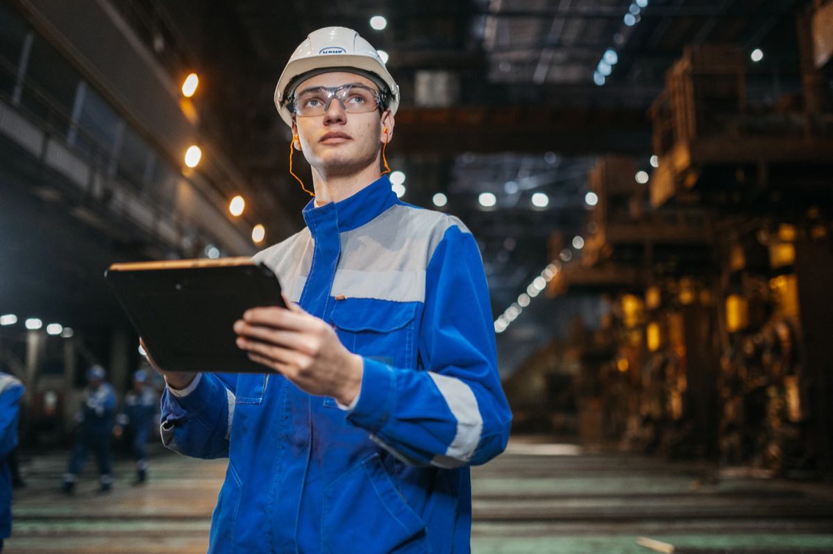 Engineer verifying equipment status on a tablet in a production facility