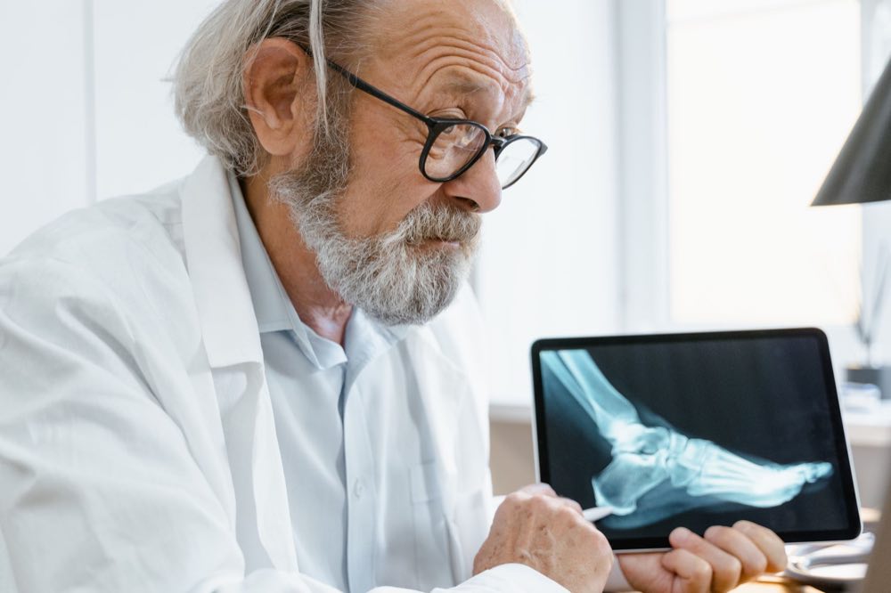 A senior doctor in a white coat discussing results on a laptop with a colleague