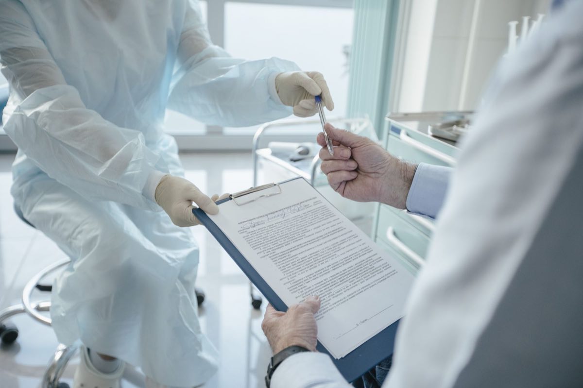 A clinician handing a consent form to a patient for signature