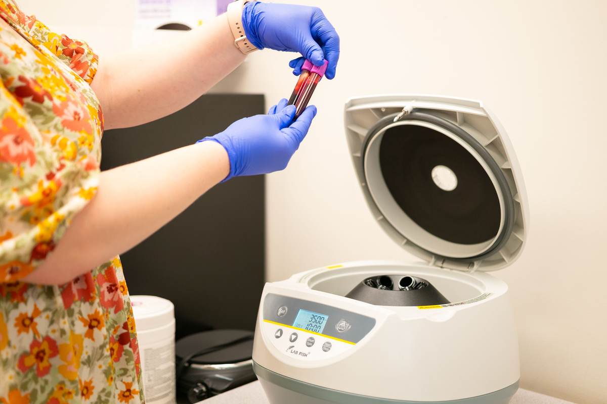 A lab technician placing blood samples in a centrifuge