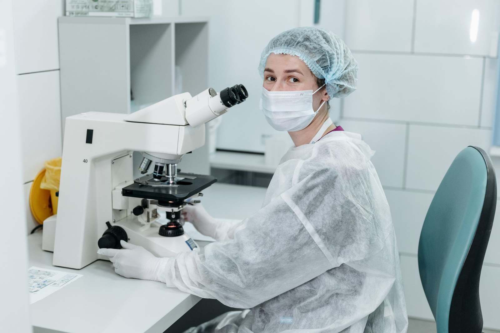 A scientist working with a microscope in a sterile laboratory environment