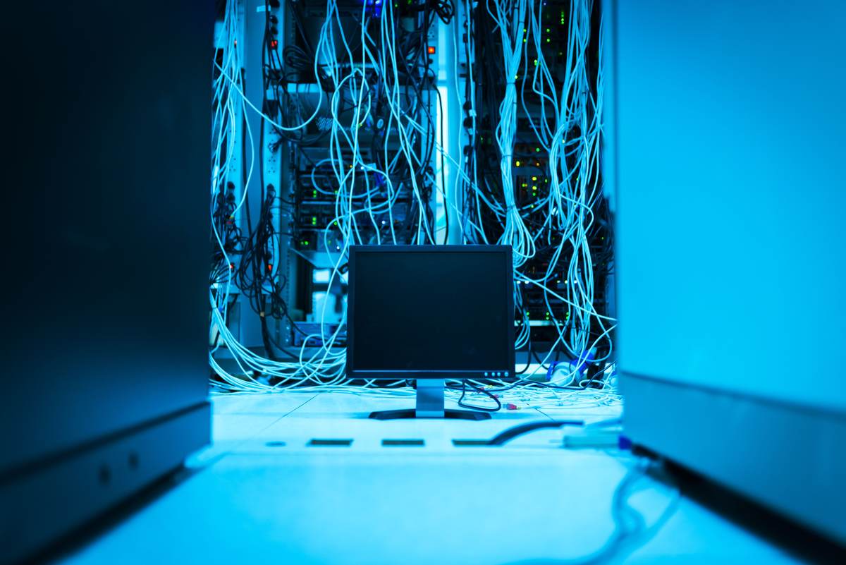 A network of cables in a data center with a monitor in the foreground