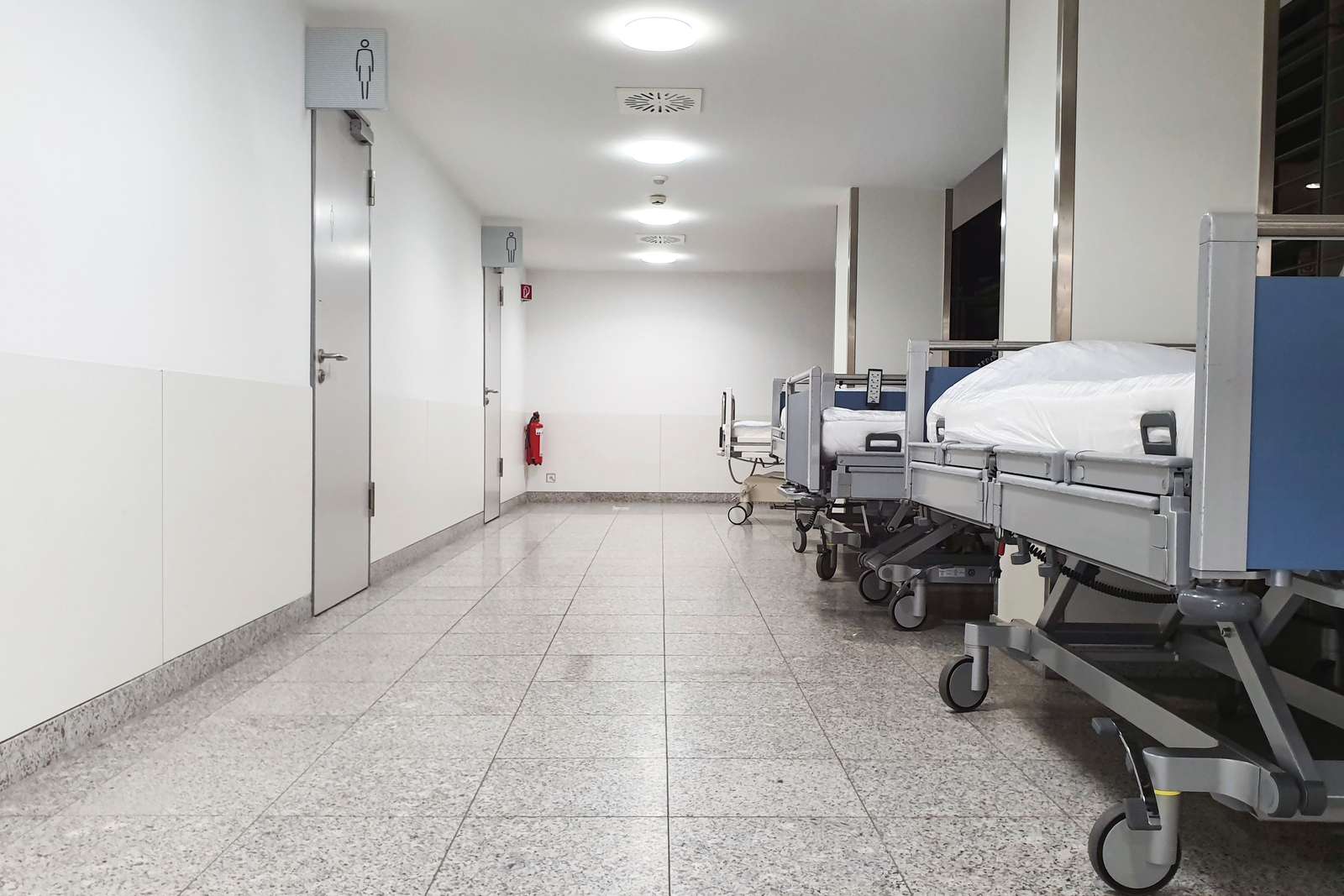 A modern hospital corridor with empty medical beds along the wall