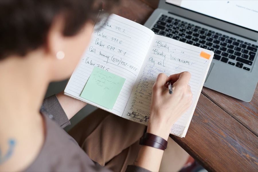 Professional writing notes beside a laptop
