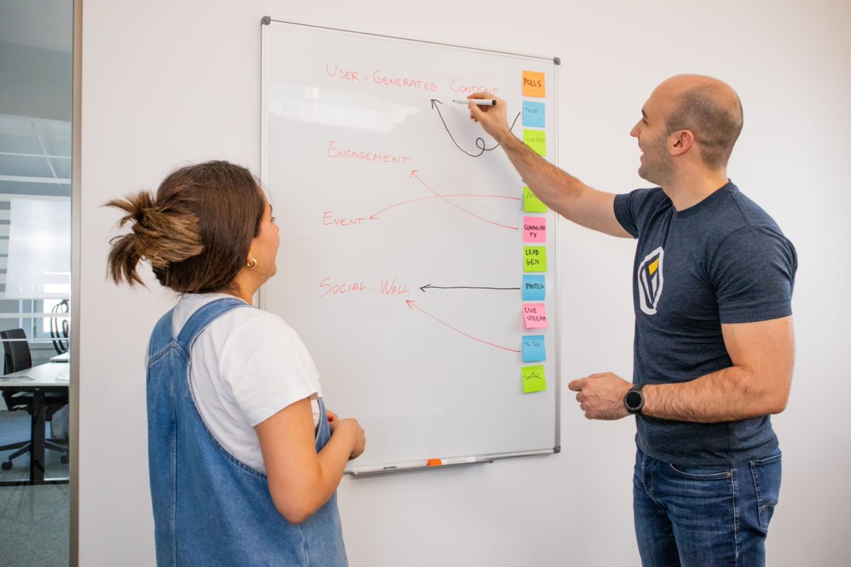 Two colleagues working through a plan at a whiteboard