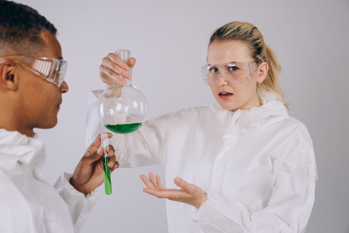 Two scientists in protective gear conducting an experiment together