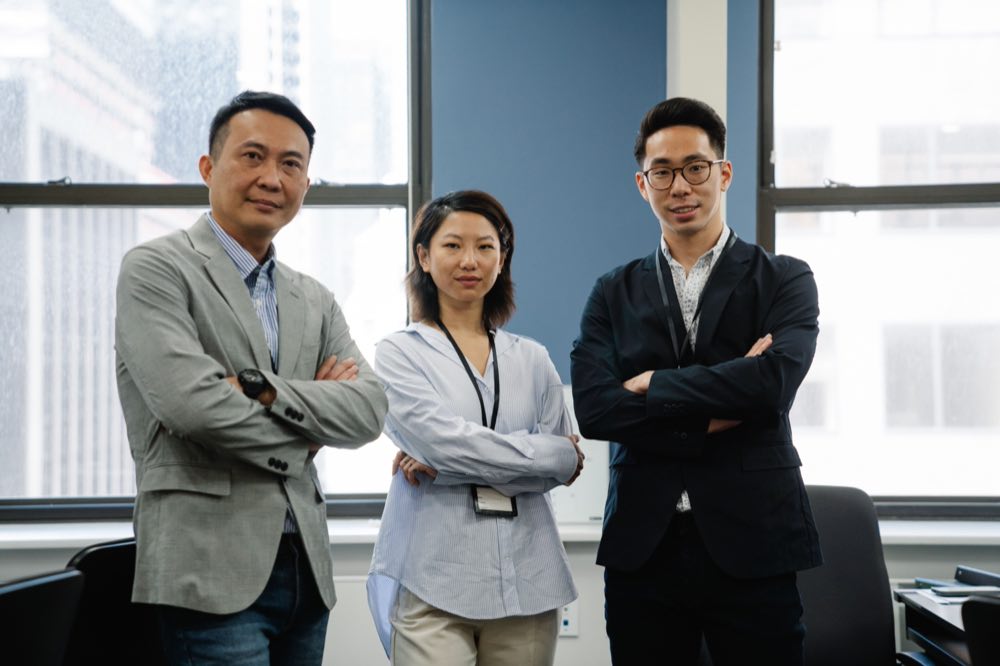 Three professionals standing together in a bright office