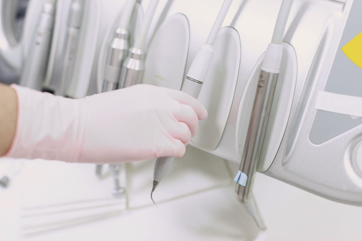 Close-up of a gloved hand operating dental tools in a sterile clinic environment
