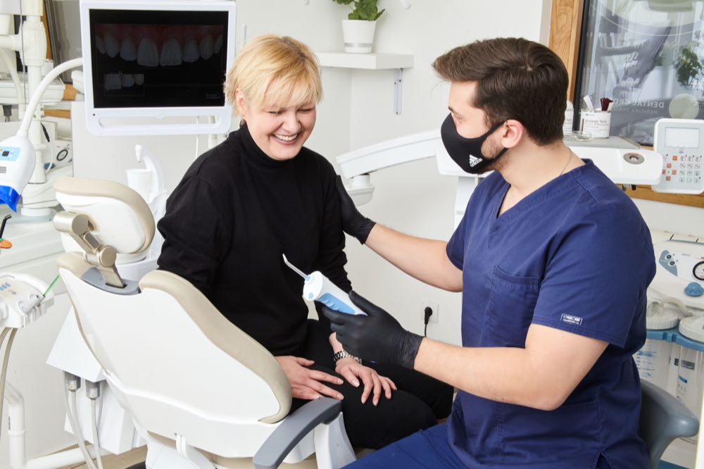 A dentist in Belgrade offers a friendly consultation to a smiling patient in a modern clinic