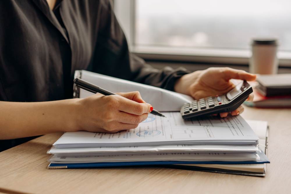 A person using a calculator over financial documents in an office