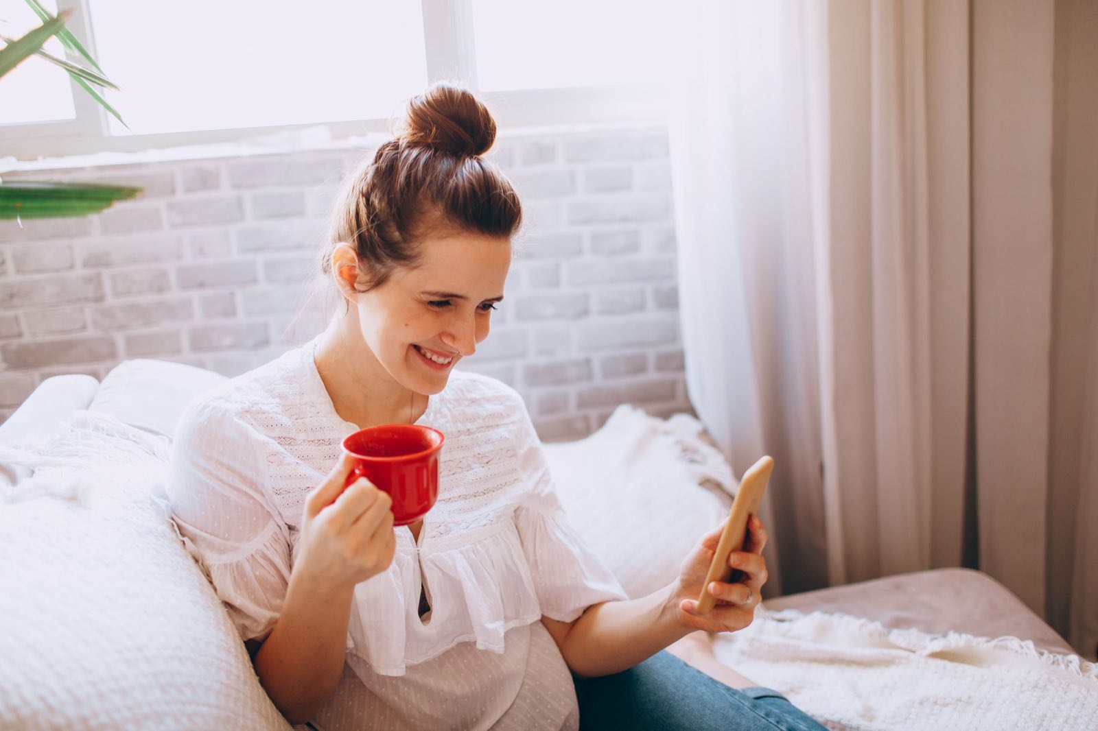 A woman on a bright sofa using a therapy program on her smartphone