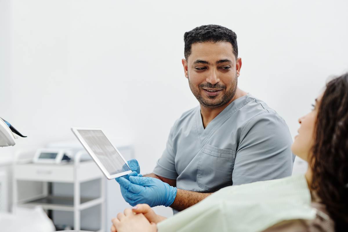A nurse using a digital tablet during a patient consultation in a clinic