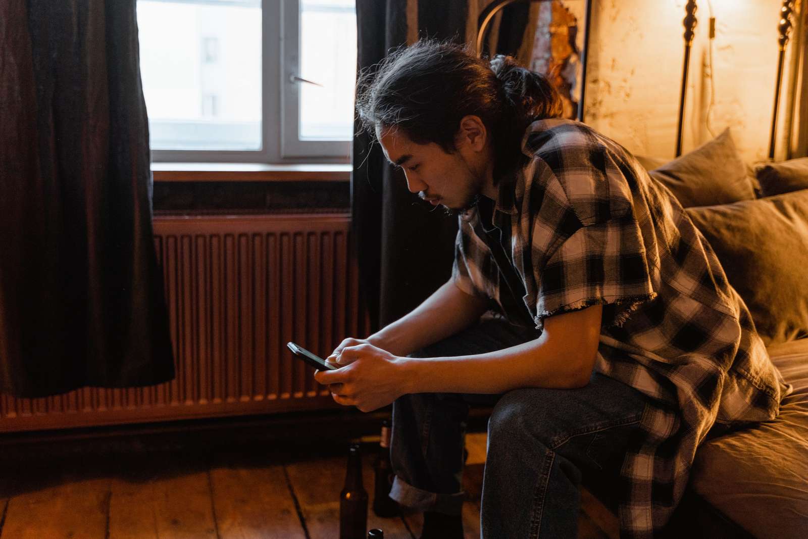 A man using a smartphone while sitting in a cozy bedroom