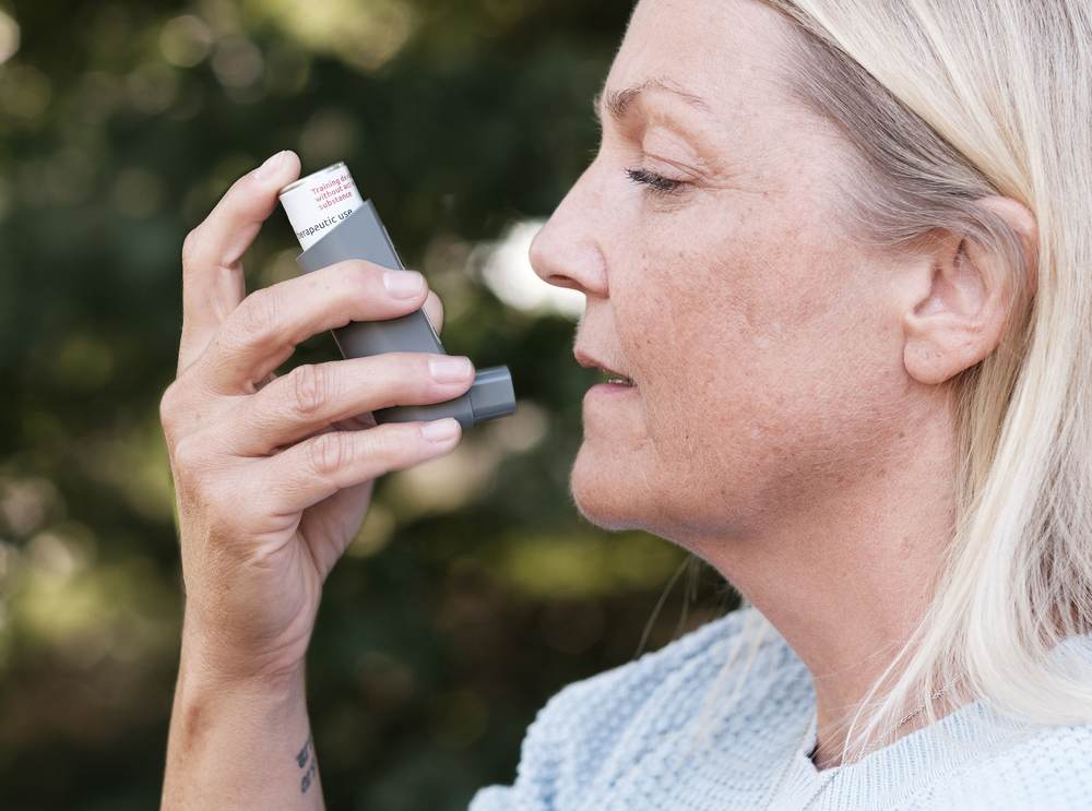 A person self-administering with an inhaler outdoors