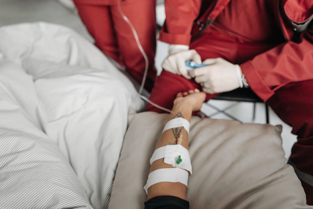 Clinician adjusting an intravenous line at a patient's bedside