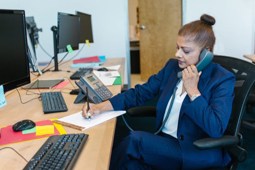 A compliance professional working through paperwork at an office desk