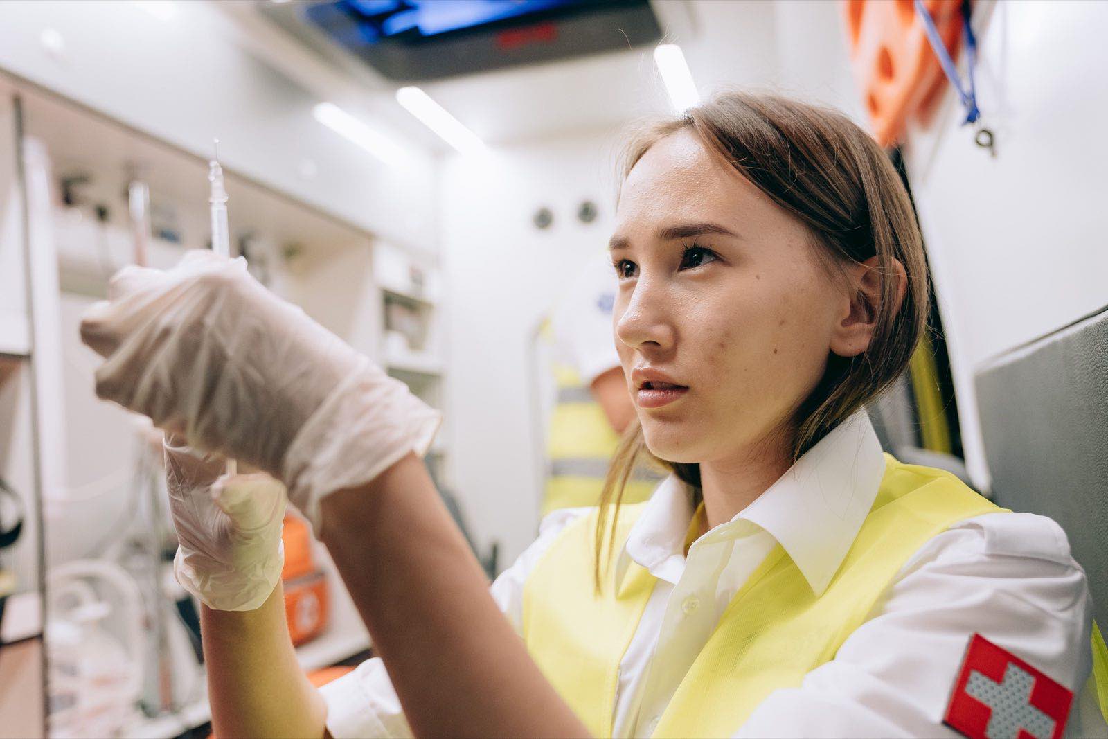 A paramedic preparing a syringe inside an ambulance