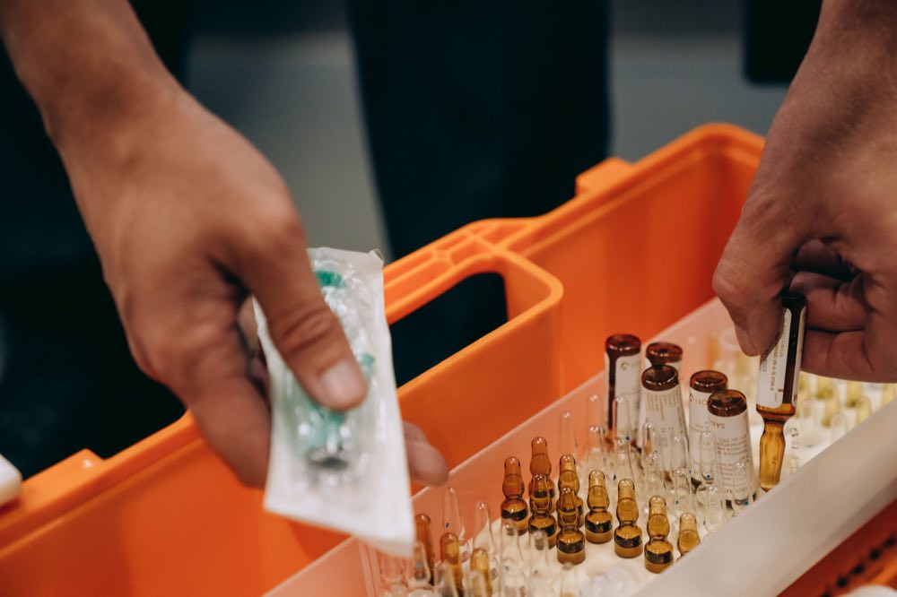 Hands organizing vials and a syringe in a medical setting