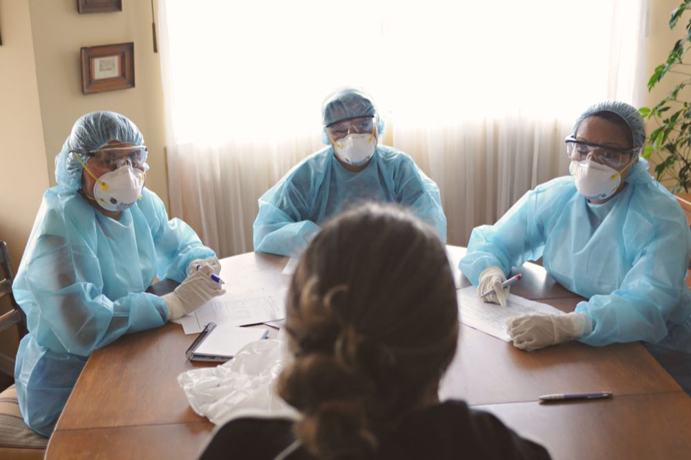 Healthcare workers in protective gear conferring about patient care