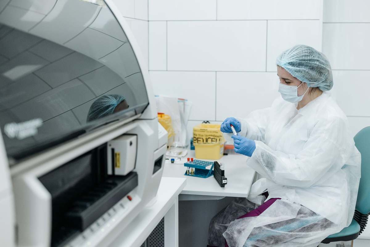A gowned scientist operating genomics equipment in a laboratory