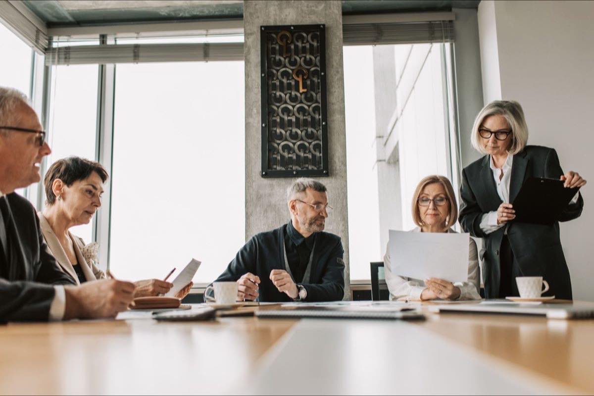 A senior leadership team reviewing program documents around a boardroom table
