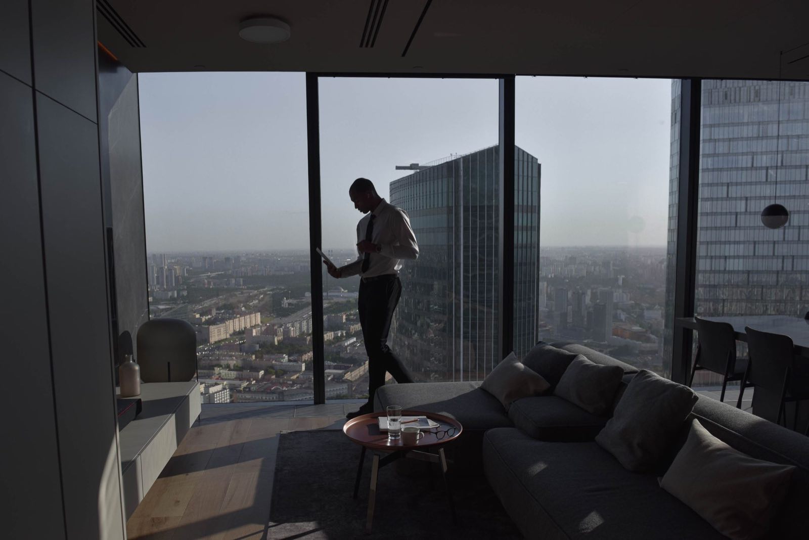 An executive reads a briefing document at a floor-to-ceiling window above the city