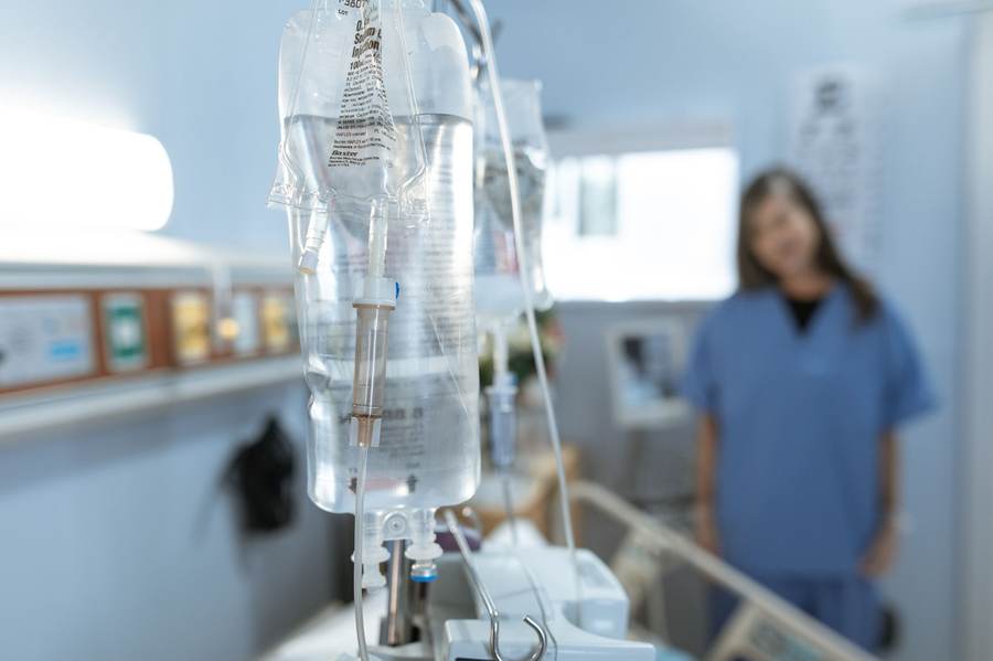 Intravenous infusion line in a hospital with a nurse in the background
