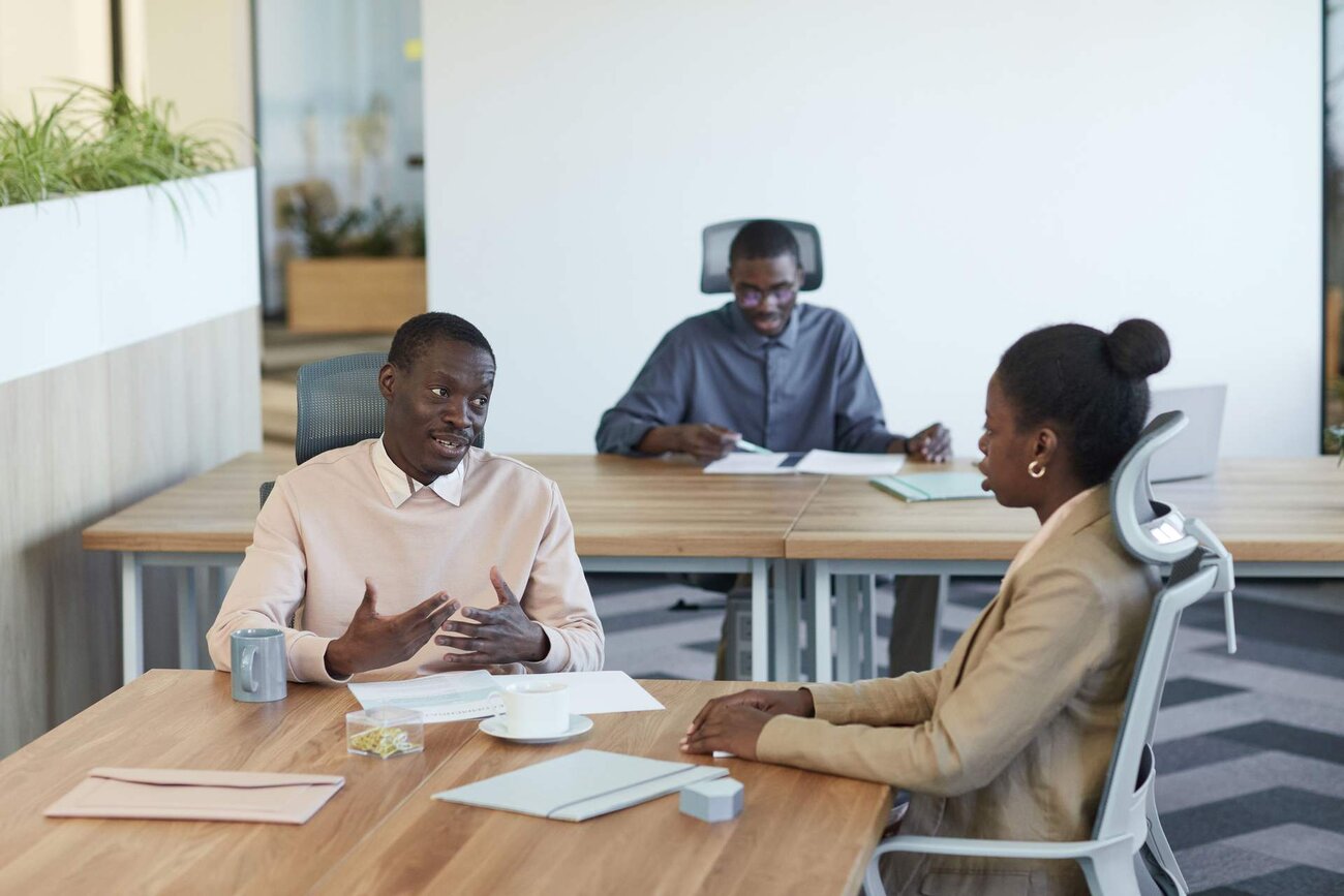 Three colleagues discussing documents at a table in a bright office