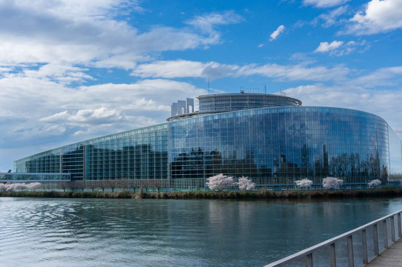 The glass facade of the European Parliament building in Strasbourg reflected in the river
