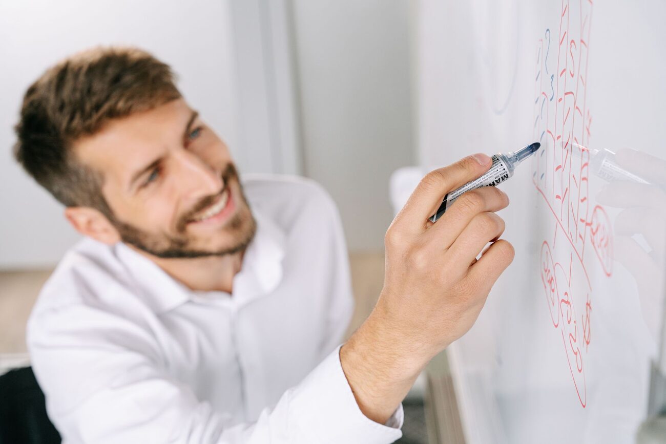 Smiling man mapping out a strategy on a whiteboard