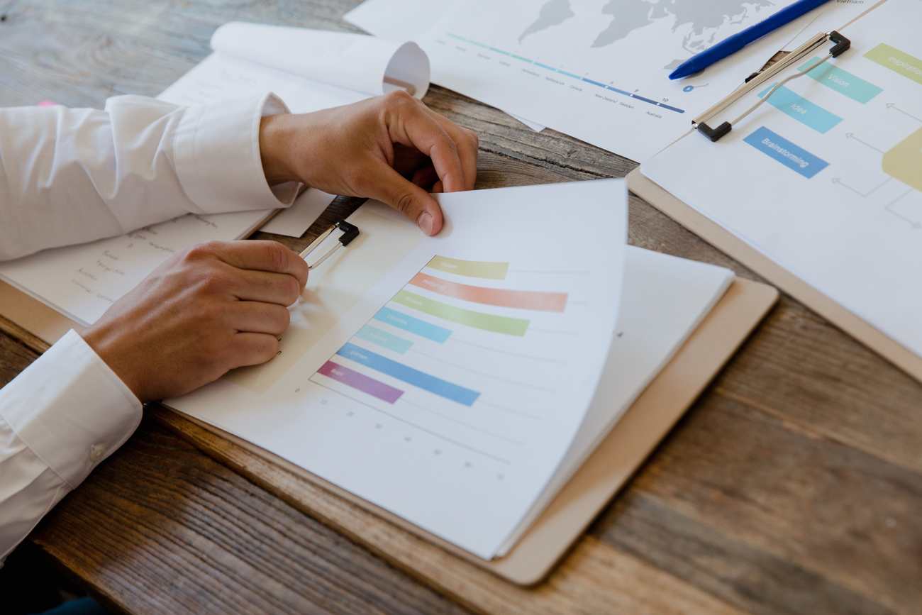 Hands reviewing printed charts and reports on a desk