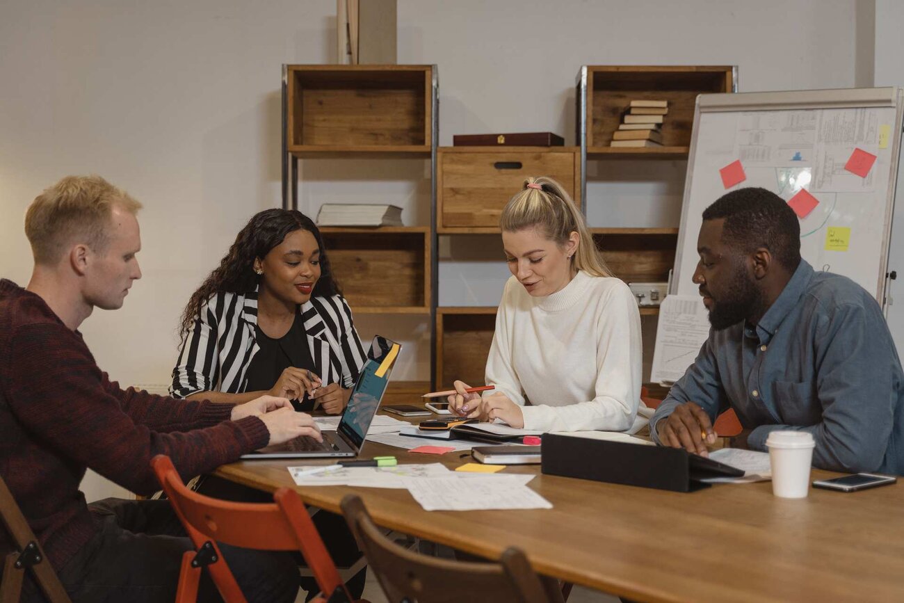 Four colleagues planning around a table with a laptop and flipchart