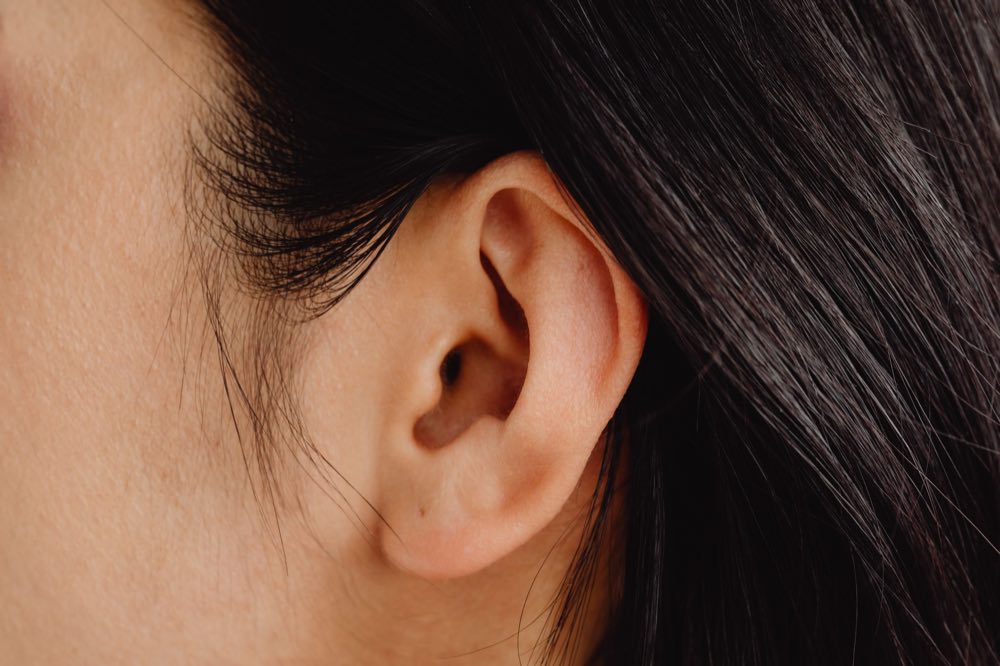Detailed close-up photo showcasing a human ear with dark hair