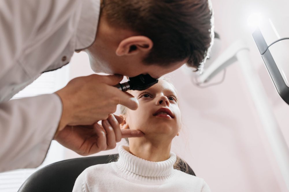 Doctor performs an eye examination on a young girl in a clinic setting, showcasing pediatric healthcare